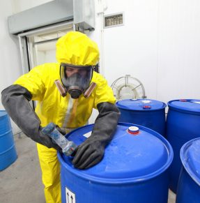 man in hazard suit opening large containers