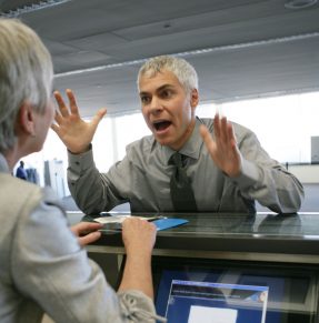 main gesturing as he speaks to receptionist