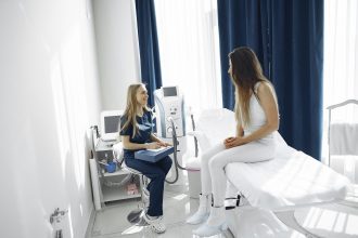woman in blue scrubs helping patient sitting on bed